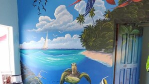 A room with a mural of a tropical beach scene, including a turtle, fish, and birds. - Mr. Ed's Adventures Belize (San Pedro)