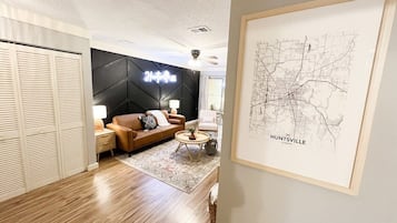 A modern living room with a sofa, coffee table, and a map of Huntsville on the wall.