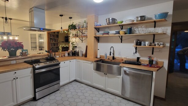 Una cocina moderna con armarios blancos, una estufa de acero inoxidable y un suelo de baldosas hexagonales.