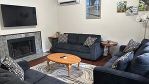 A living room with a fireplace, a sofa set, a coffee table, and a flat-screen TV. - Sasquatch Sanctuary (Crescent City)