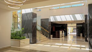 A modern lobby with marble flooring, a reception desk, and a staircase with glass railings. - Ocean Grand Hotel (Ramallah)