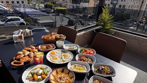 A rooftop dining table with various dishes, a view of the cityscape, and a clear sky. - Ocean Grand Hotel (Ramallah)