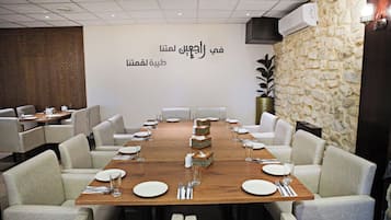 Un salón de conferencias con una mesa larga, sillas y una pared decorativa con texto árabe.