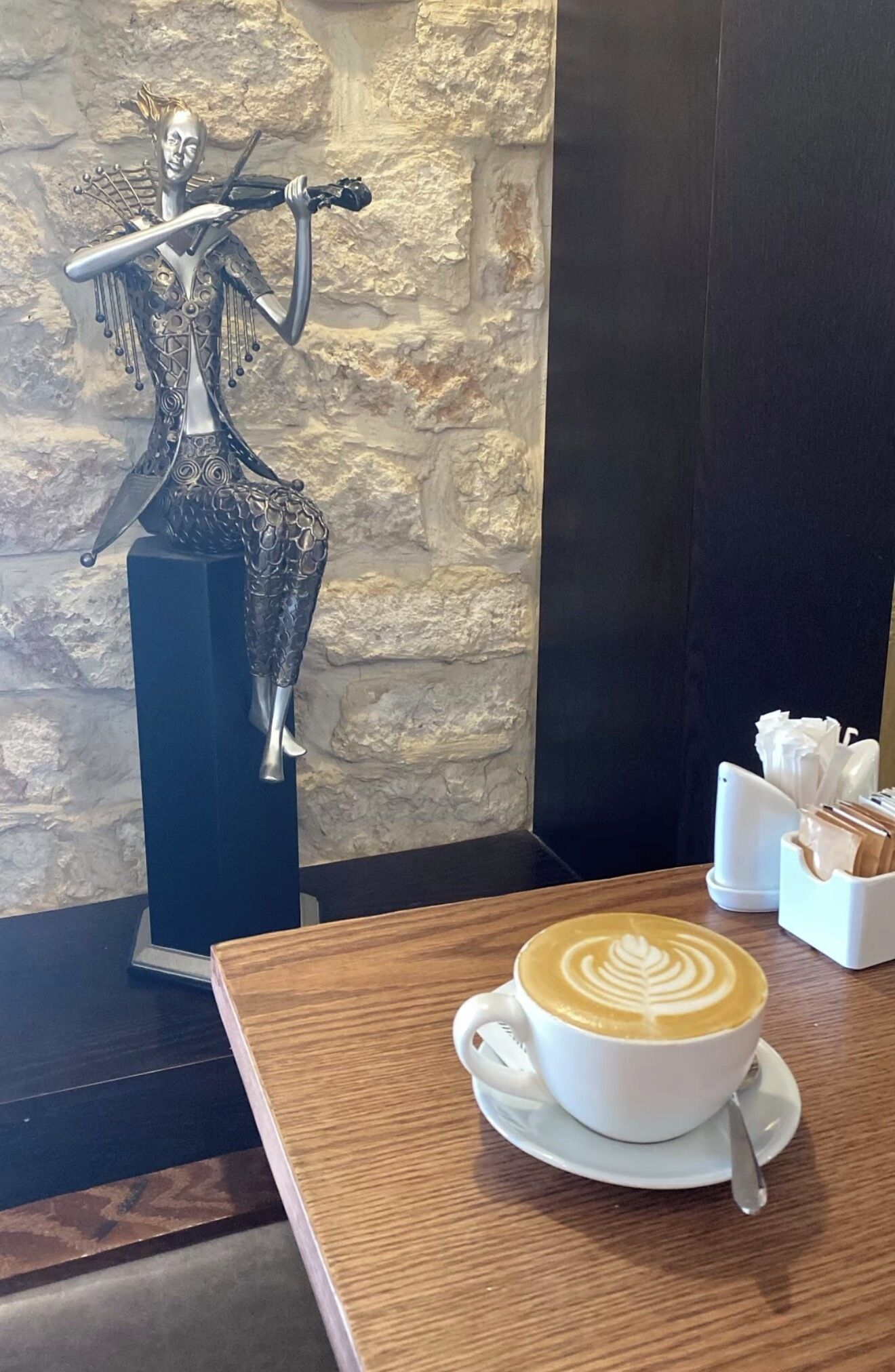 A table with a cup of coffee and a decorative metal sculpture.