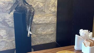 A table with a cup of coffee and a decorative metal sculpture.