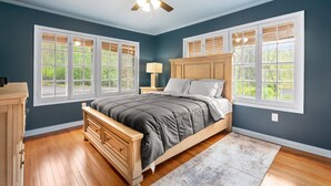 Un dormitorio con cama, mesitas de noche, cómoda y ventilador de techo.
