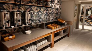 A buffet setup with coffee makers, glassware, and serving trays.