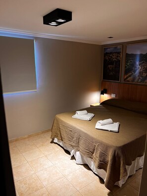 Une chambre d’hôtel avec un lit, une fenêtre et deux tableaux accrochés au mur.