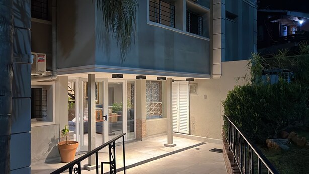 A building entrance with glass doors, a staircase, and potted plants.