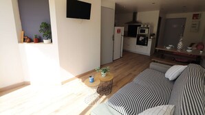 Een moderne woonkamer met een bank, een salontafel en een aan de muur bevestigde televisie.