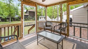 A covered outdoor deck with a glass enclosure, wicker furniture, and a view of a residential area. - 🏖️Beautiful Home near OC & Assateague Park 🏖️ (Ocean Pines)