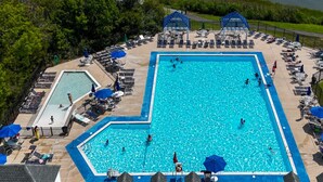 A large rectangular swimming pool surrounded by lounge chairs and umbrellas, with a separate smaller pool and a covered area in the background. - 🏖️Beautiful Home near OC & Assateague Park 🏖️ (Ocean Pines)