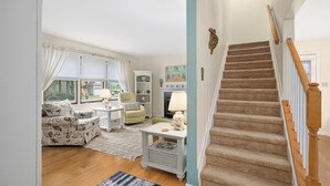 A living room with a sofa, armchair, and a staircase with carpeted steps. - 🏖️Beautiful Home near OC & Assateague Park 🏖️ (Ocean Pines)