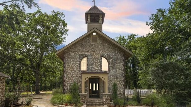 A stone church with a bell tower, a central entrance, and a surrounding garden. - The Franklin Castle (Tahlequah)