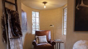 A cozy room with a leather armchair, a small table with a lamp, and a painting on the wall. - The Franklin Castle (Tahlequah)
