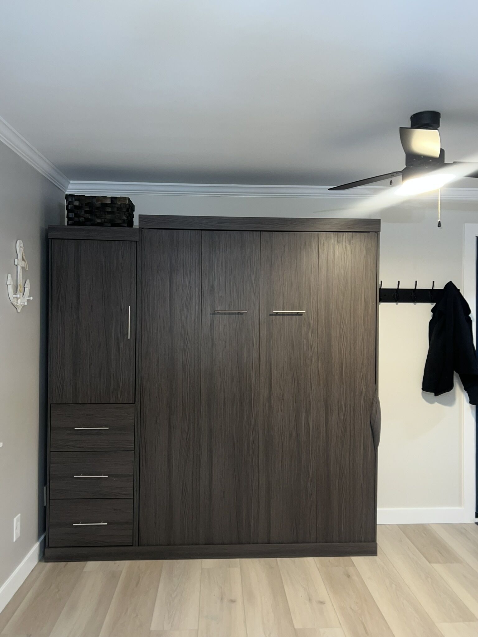 A room with a large wardrobe, a ceiling fan, and a coat rack.
