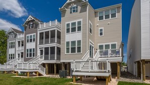 A row of multi-story residential buildings with balconies and a grassy lawn. - Recently Built  Rehoboth Beach Townhouse Pool Parking Sleeps 16 (Rehoboth Beach)