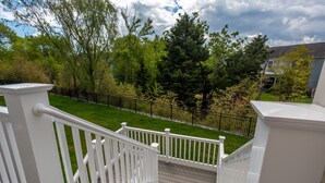 A wooden deck with white railings overlooking a well-maintained lawn and a black metal fence. - Recently Built  Rehoboth Beach Townhouse Pool Parking Sleeps 16 (Rehoboth Beach)
