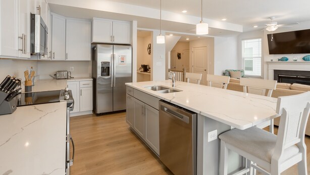 A modern kitchen with white cabinets, stainless steel appliances, and a central island with a sink. - Recently Built  Rehoboth Beach Townhouse Pool Parking Sleeps 16 (Rehoboth Beach)