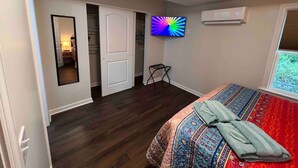 Un dormitorio con cama, televisión, puerta y ventana.