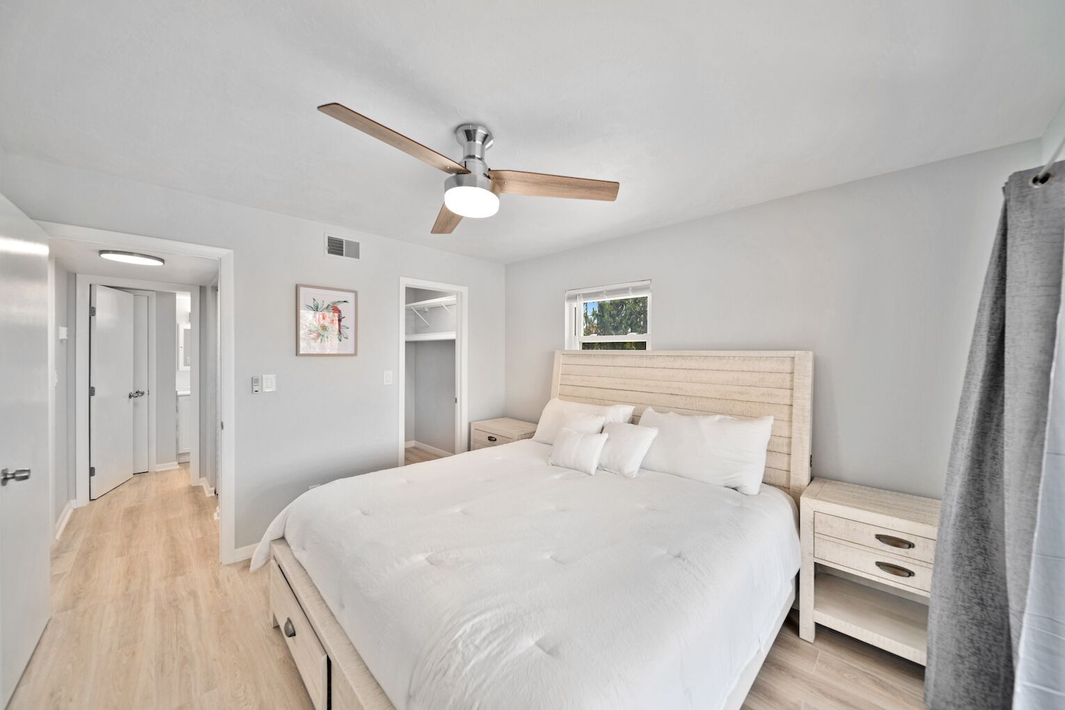 Una camera da letto con un letto, una ventola a soffitto, un comodino e una finestra.