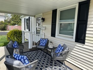 A covered porch with outdoor furniture, a patterned rug, and a view of the house. - Sea Turtle Getaway (Ventnor City)