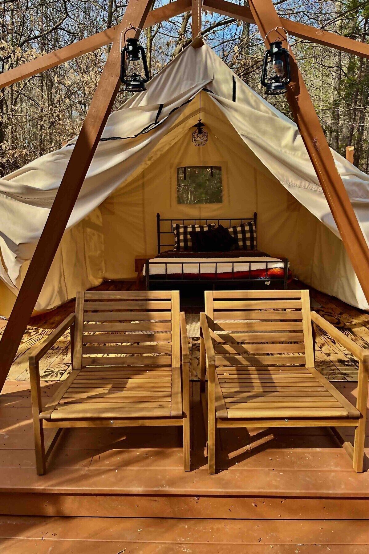Une tente avec deux bancs en bois et un lit à l’intérieur.