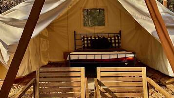 A tent with two wooden benches and a bed inside.