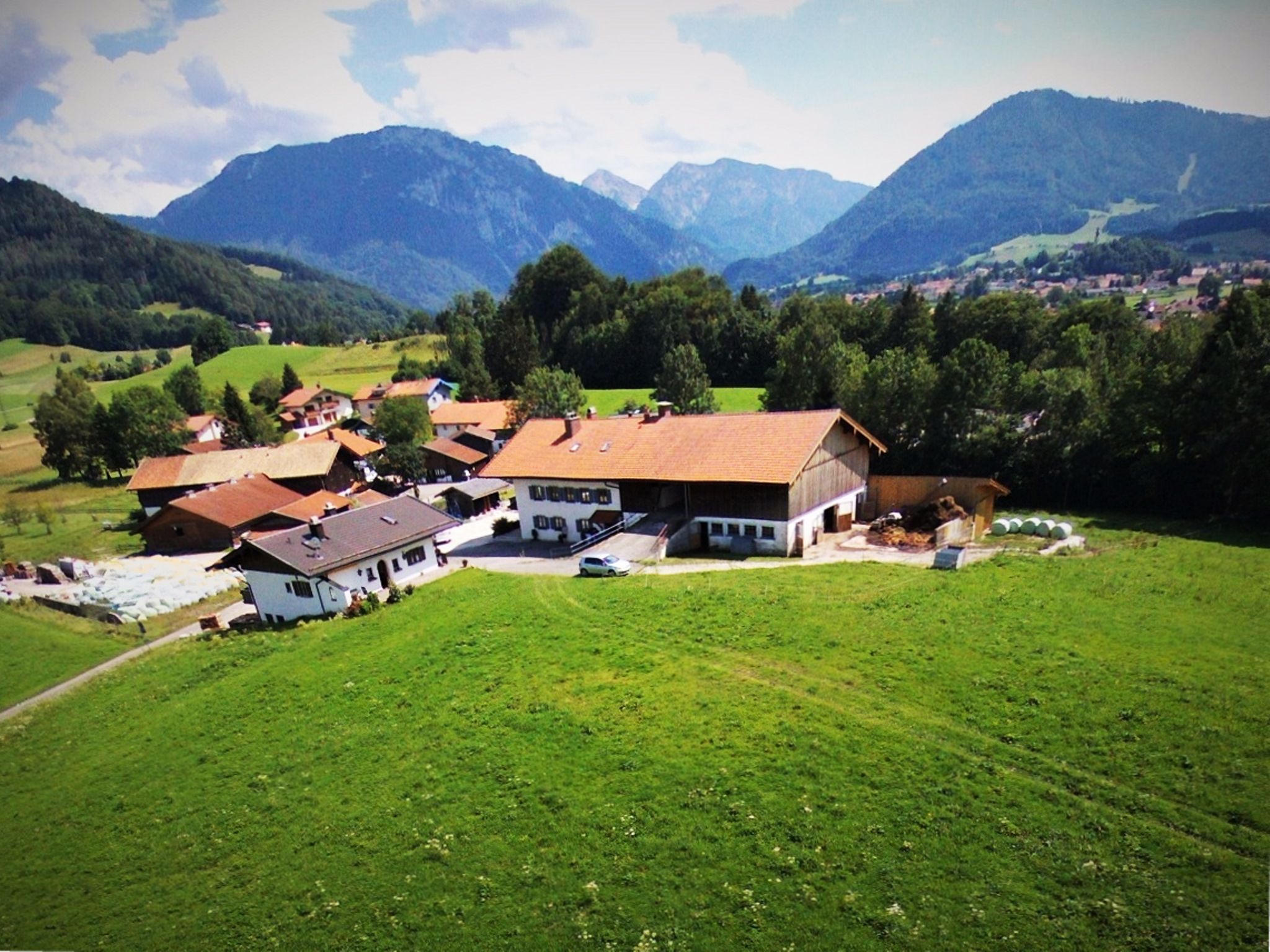 Ein ländliches Dorf mit Häusern und einer Scheune, umgeben von Bergen.