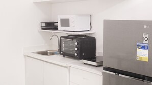 A modern kitchen with white cabinets, a microwave, a toaster, and a stainless steel refrigerator. - Prima at Primavera City (Cagayan de Oro)