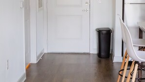 Une cuisine moderne avec des meubles blancs, un réfrigérateur en acier inoxydable et une table à manger en bois, assortie de chaises.