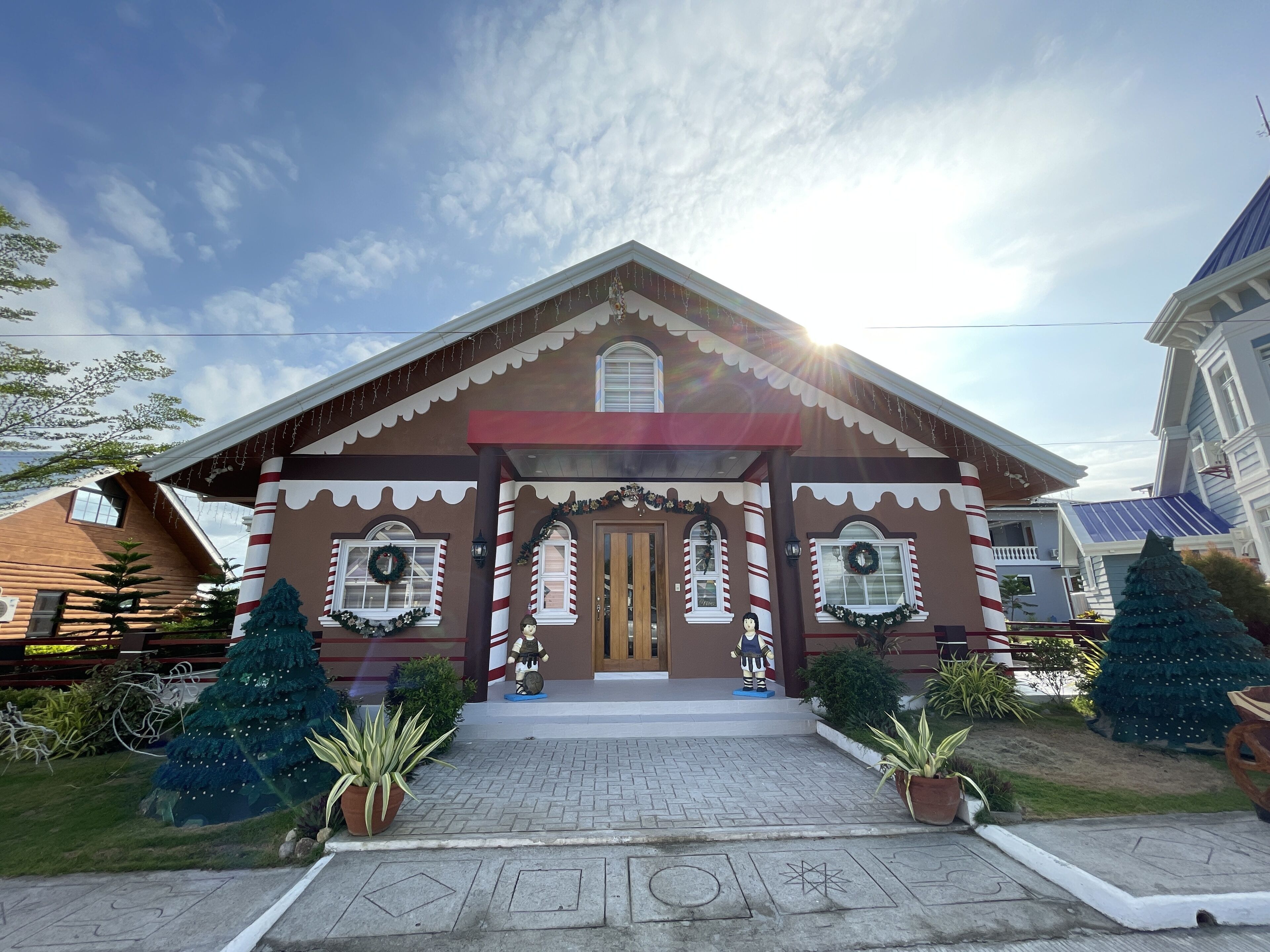 A gingerbread house with a red roof, white trim, and striped columns.