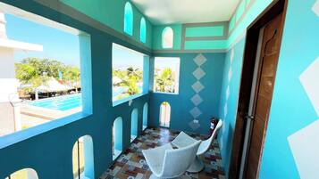A room with a view of a swimming pool, a white wicker chair, and a patterned floor.