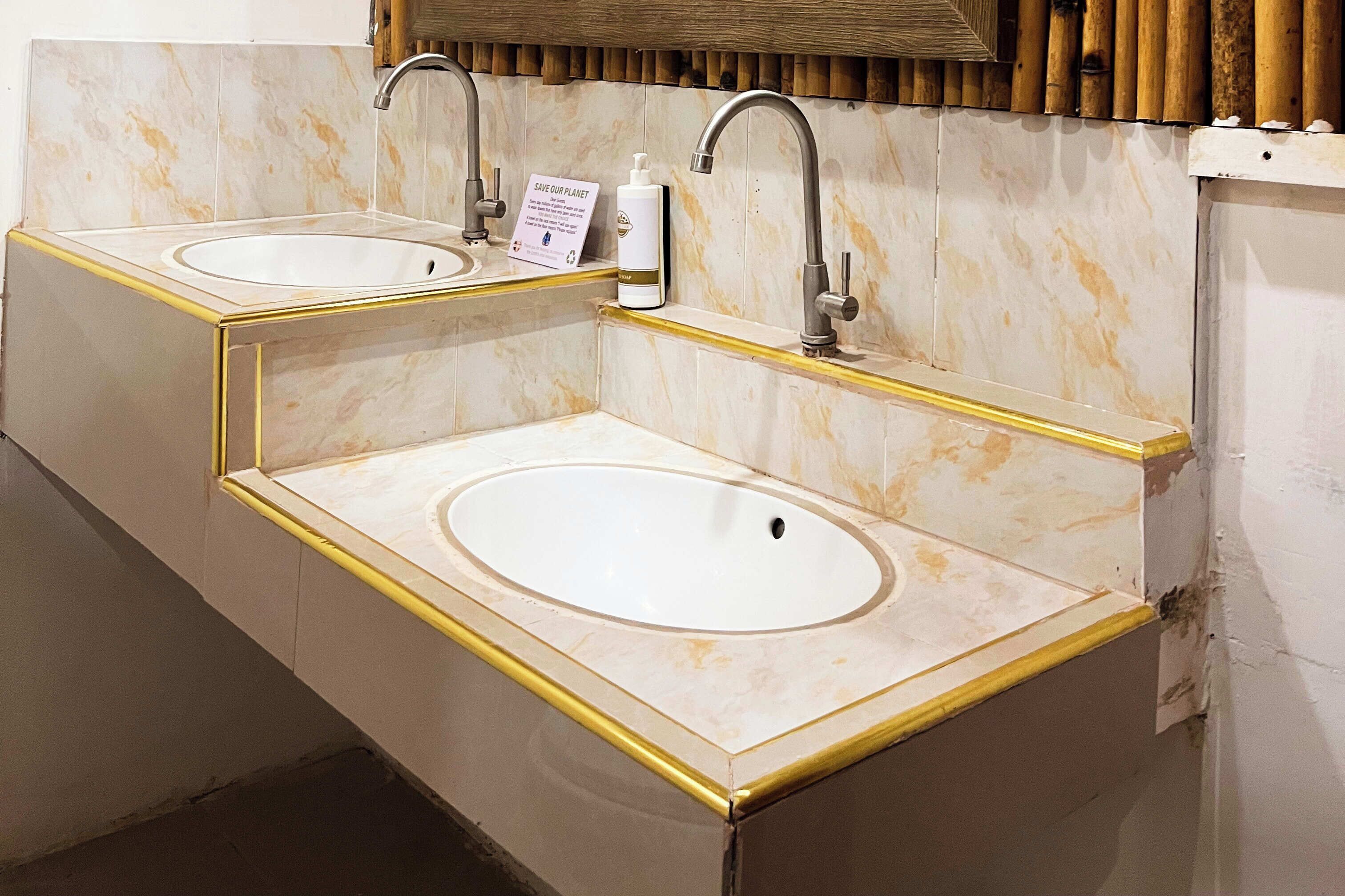 Un baño con dos lavamanos, un espejo y un letrero que dice 'SAVE OUR PLANET'.