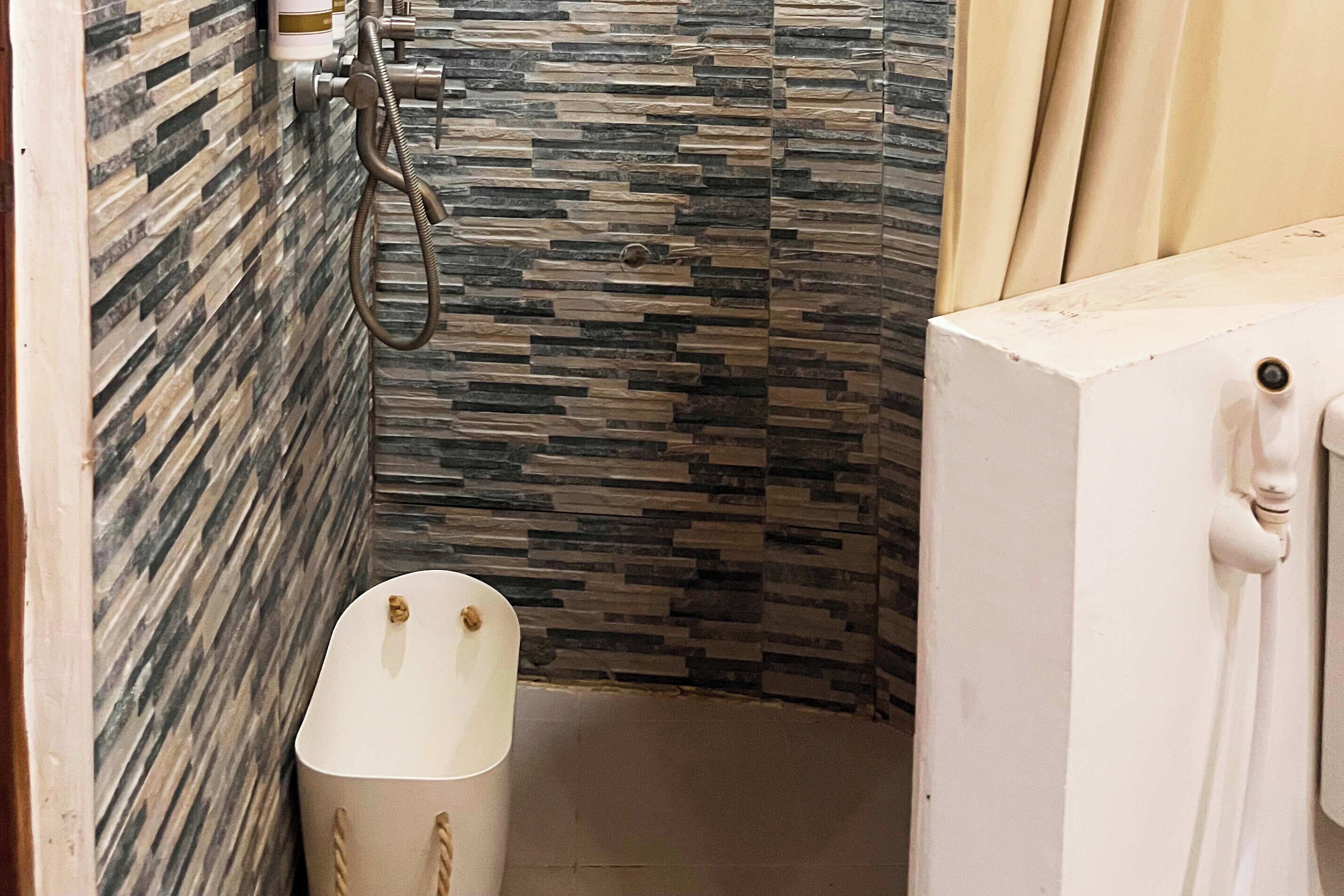 A bathroom with a shower area, a white bathtub, and a towel rack.