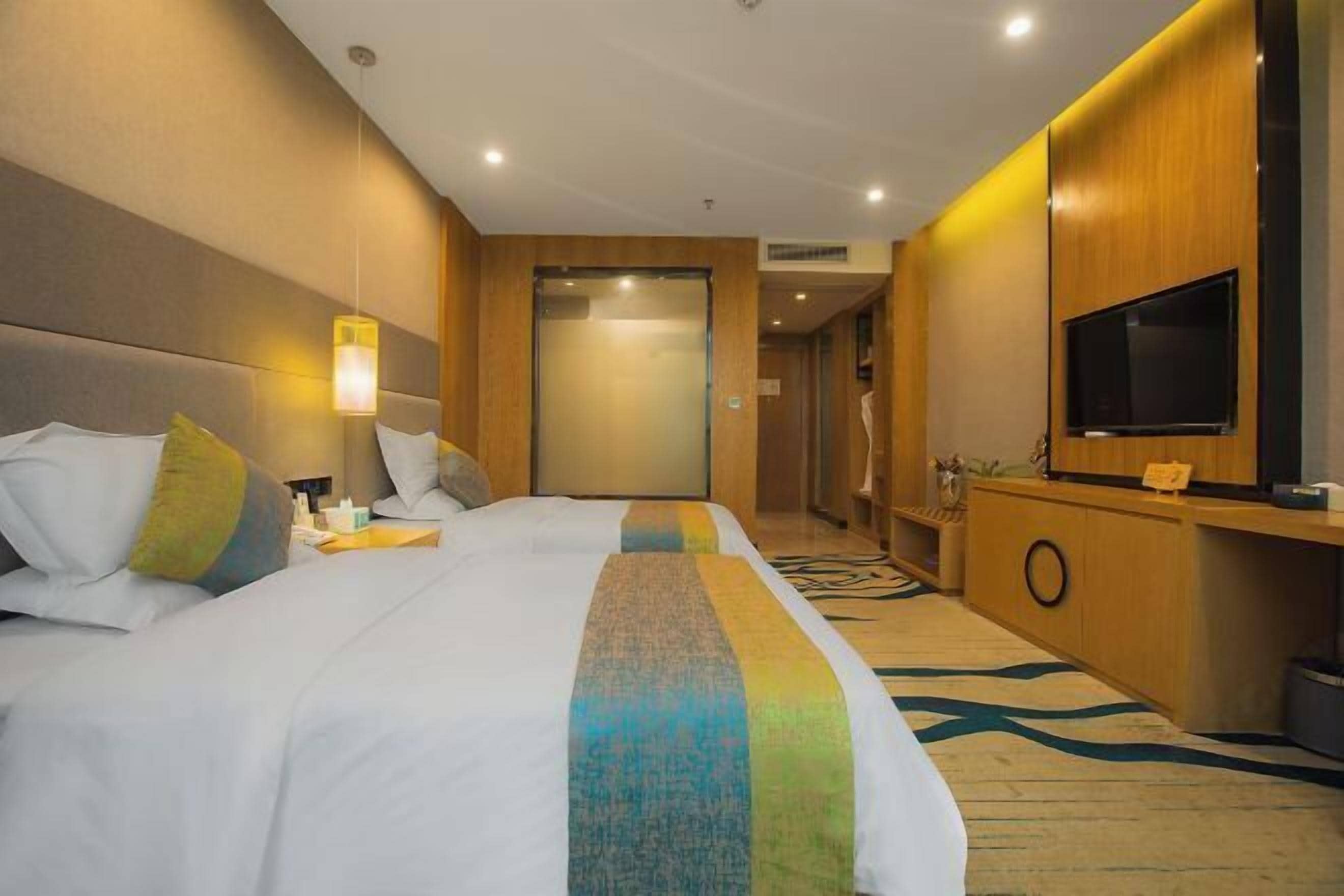 A hotel room with two beds, a TV, a desk, and a bathroom.