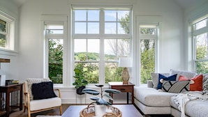 A living room with a large window, a sofa, a chair, a coffee table, and a side table.