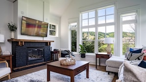 A living room with a fireplace, large windows, and a view of the outdoors.