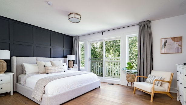 A bedroom with a large bed, bedside tables, a chair, and a window with curtains.