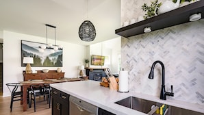 A modern kitchen with a large island, black cabinetry, and a herringbone tile backsplash.