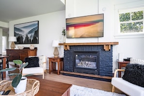 A living room with a fireplace, two large paintings, and a cozy seating area.