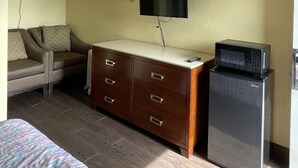 Ett hotellrum med en säng, en soffa, en byrå, en tv och ett kylskåp.