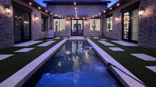 Une maison moderne dotée d’une piscine, de murs en pierre et d’un éclairage extérieur.