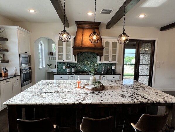 A kitchen with a large island, built-in appliances, and pendant lighting.