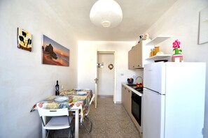 Une cuisine équipée d’une table à manger pour deux personnes, d’un réfrigérateur et d’un four à micro-ondes.