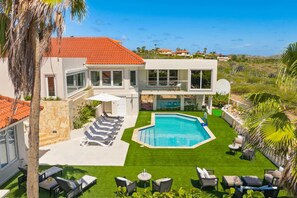 A modern two-story house with a swimming pool, outdoor seating, and a view of the surrounding landscape. - Aruba Beach Retreat by Bocobay (Noord)