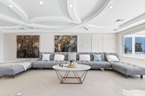 Ein modernes Wohnzimmer mit einem grauen Ecksofa, einem runden Couchtisch und zwei großen abstrakten Gemälden.