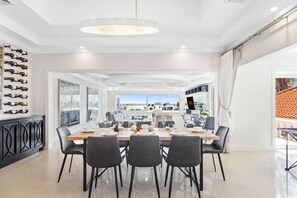 A modern dining area with a large table, chairs, and a view of the outdoors.