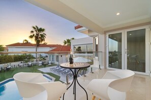 Ein Balkon mit Pool, weißen Stühlen und einem Tisch mit einer Flasche.