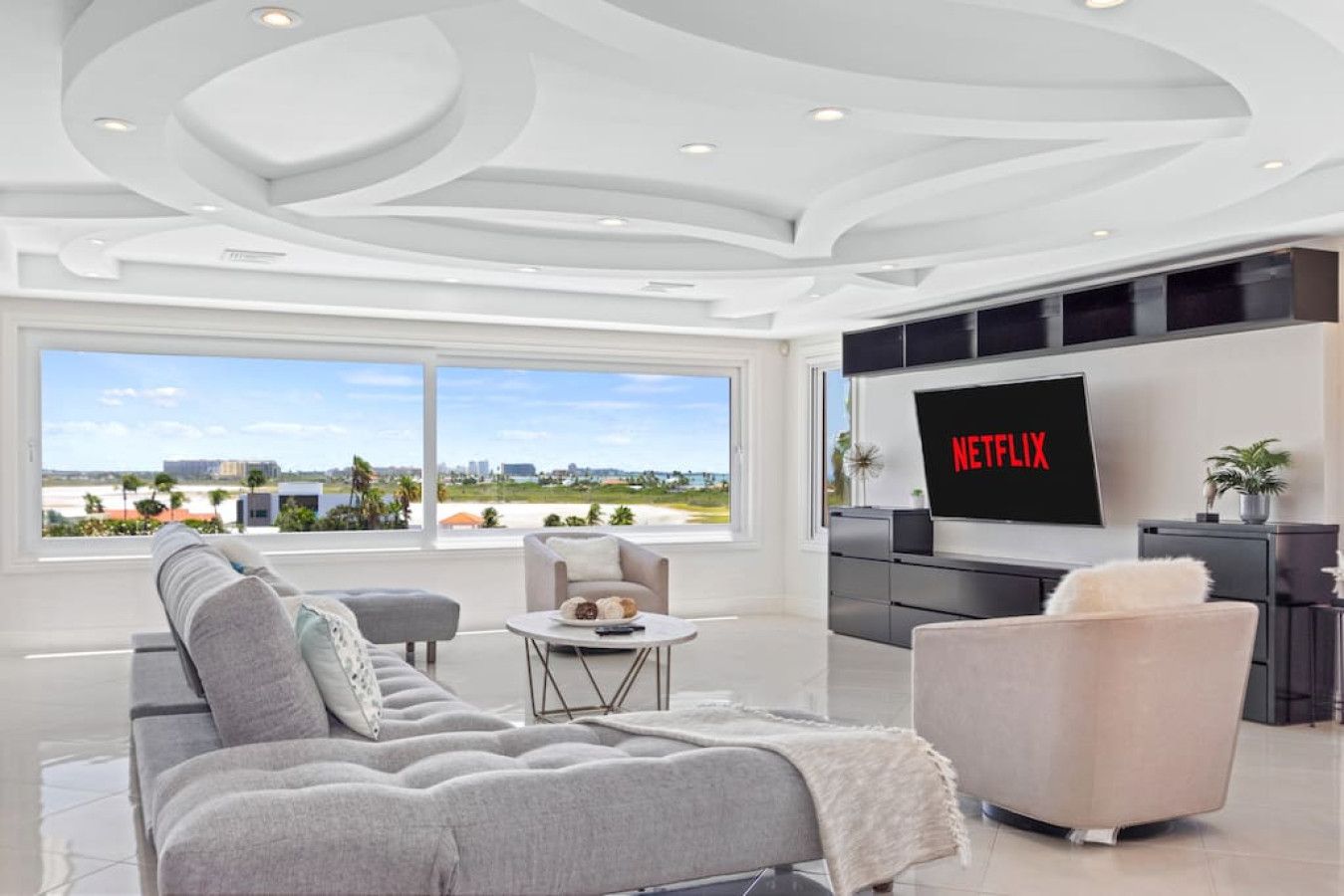 A modern living room with a large window, a flat-screen TV, and a sofa.